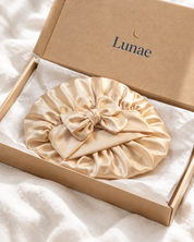 Bonnet de nuit Lunae en satin champagne posé sur son carton Lunae
